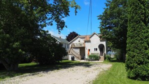 A two-story house with a front porch and a covered outdoor seating area. - The Cute & Cozy - Lower Apt. - GREAT LOCATION!  WALK TO DOWNTOWN AND LAKE MICHIGAN! (Frankfort)