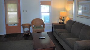 A living room with a sofa, a chair, a coffee table, a lamp, and a ceiling fan. - The Cute & Cozy - Lower Apt. - GREAT LOCATION!  WALK TO DOWNTOWN AND LAKE MICHIGAN! (Frankfort)