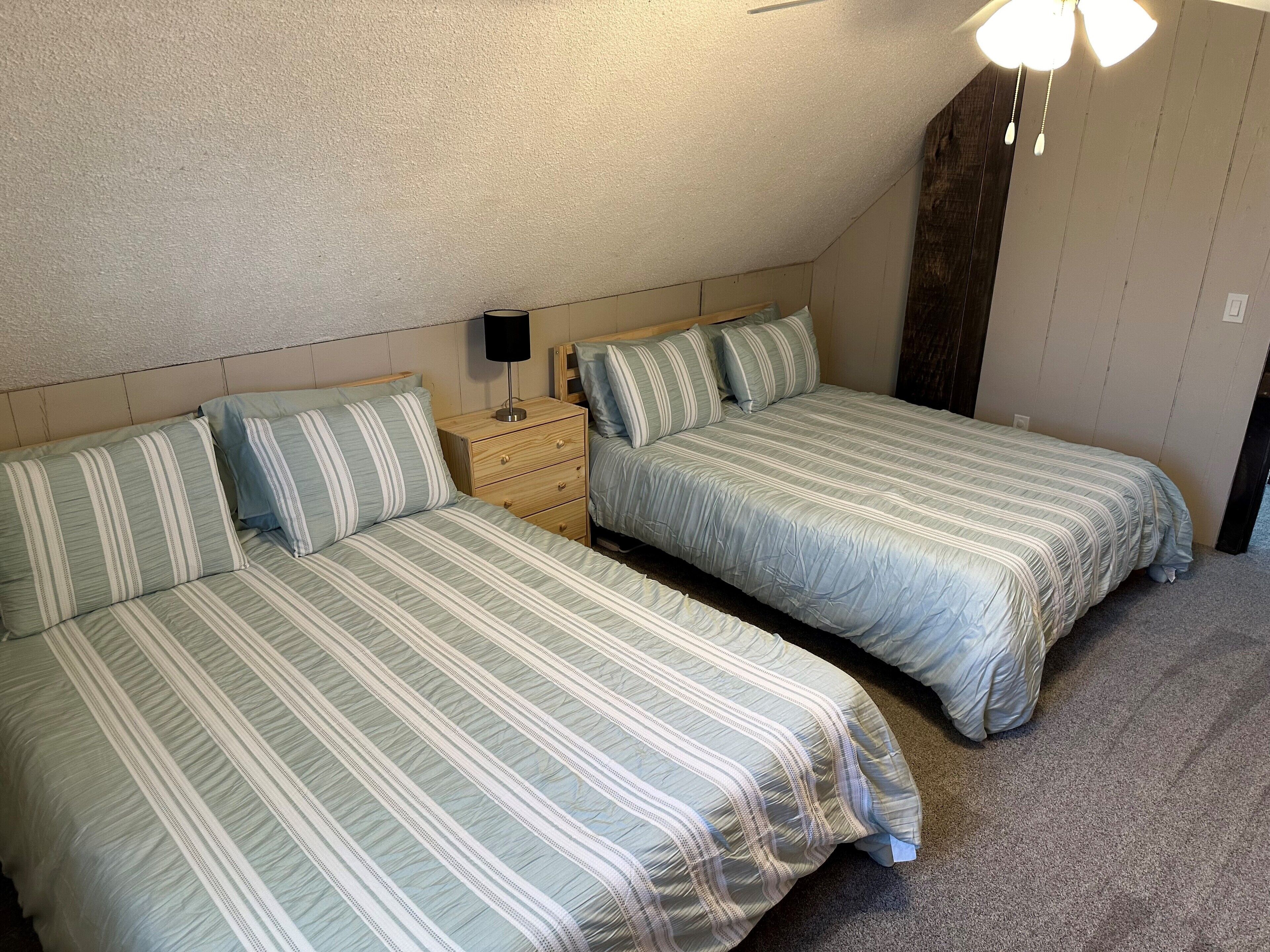 Ein Schlafzimmer mit zwei Betten, einem Nachttisch und einem Deckenventilator.