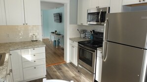 A modern kitchen with white cabinets, stainless steel appliances, and a wooden floor. - Beach Town Escape - NEWLY-REMODELED & GORGEOUS!  GREAT LOCATION AS WELL! (Frankfort)