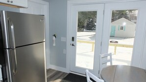 A compact kitchen with a stainless steel refrigerator, a small table, and a white chair. - Beach Town Escape - NEWLY-REMODELED & GORGEOUS!  GREAT LOCATION AS WELL! (Frankfort)