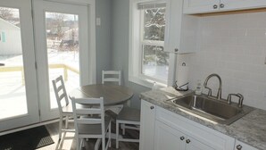 A kitchen with white cabinets, a granite countertop, a sink, and a dining area with a table and chairs. - Beach Town Escape - NEWLY-REMODELED & GORGEOUS!  GREAT LOCATION AS WELL! (Frankfort)