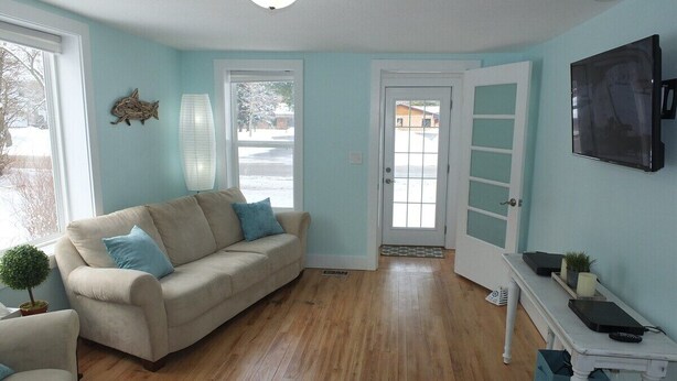 A living room with a beige sofa, a small table with a TV, and a wooden floor. - Beach Town Escape - NEWLY-REMODELED & GORGEOUS!  GREAT LOCATION AS WELL! (Frankfort)