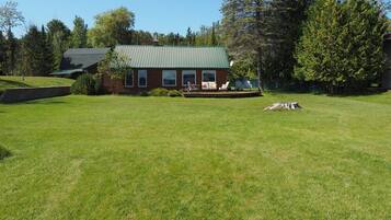 Situated in a lush landscape, this cabin features a welcoming front porch with a bench and table.
