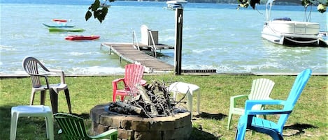 Un muelle junto al lago con un hogar, sillas y un embarcadero con barcos.