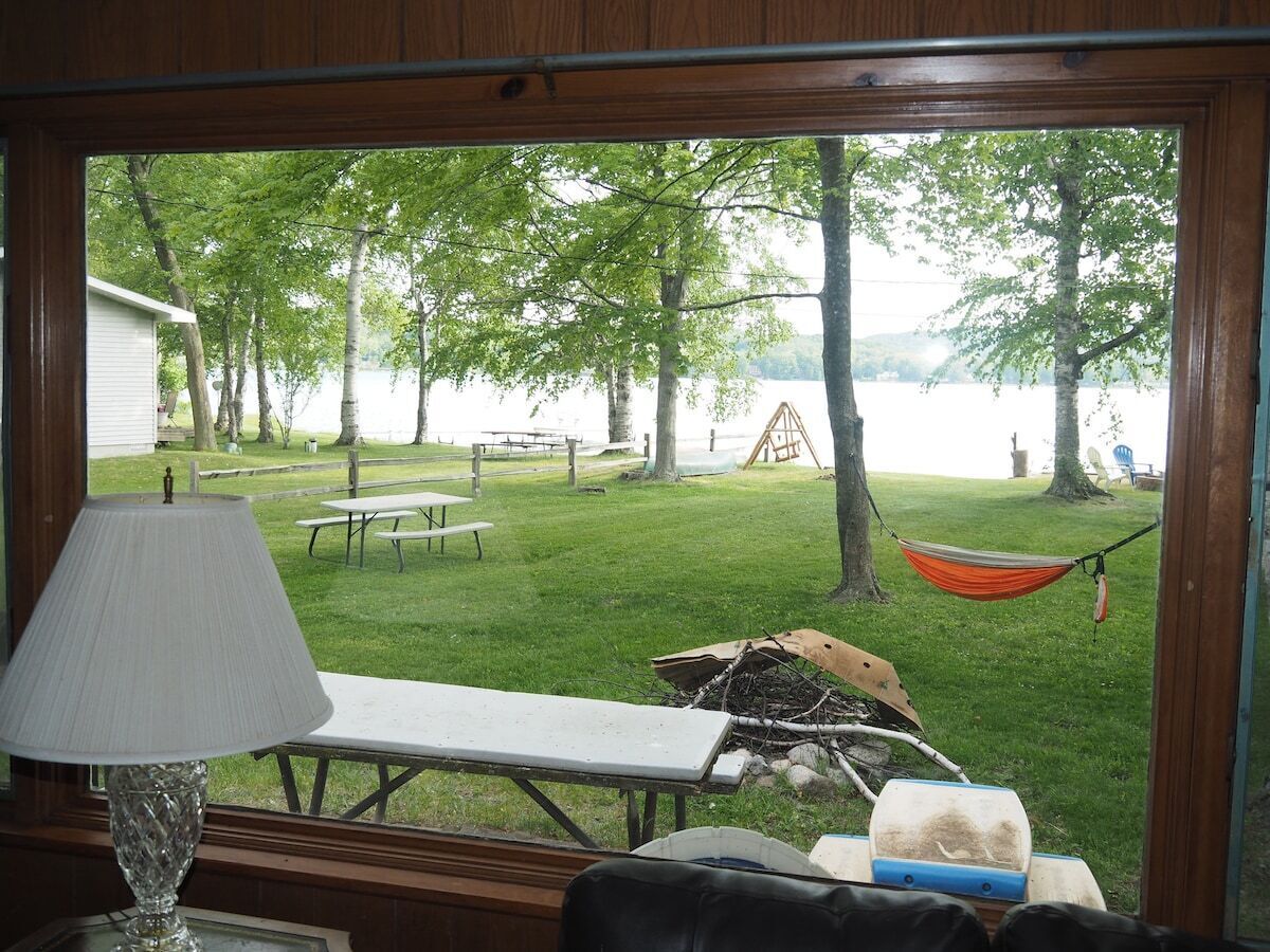 A room with a view of a grassy yard, picnic tables, and a hammock.