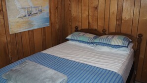 Ein Zimmer mit Holzwänden, einem Bett, Kissen und einer Decke.