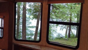 A cabin with two windows offering views of a forested area. - Twin Birch Resort - The Loon on the Lake - Lakefront with Dock, Kayak, and Rowboat! (Honor)
