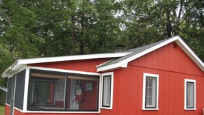 Une maison rouge à un seul étage, dotée d’une grande porte et de grandes fenêtres en verre.