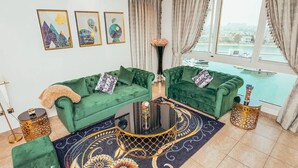 Un salon avec deux canapés verts, un tapis à motifs et une table basse ronde.
