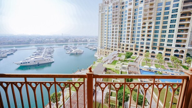 Un hôtel de grande hauteur offrant une vue sur la marina, doté de nombreux balcons et d’un espace piscine.