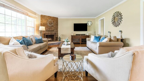 A living room with beige sofas, a coffee table, and a fireplace. - Charming Rancher, Close to Everything! (Joplin)
