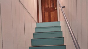 Una escalera con escalones pintados de color turquesa y una puerta de madera en la parte superior.