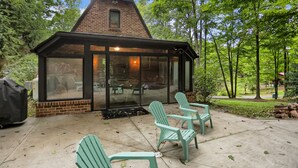 A brick building with a glass enclosure, outdoor seating with chairs, and a chimney.