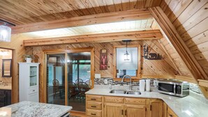 A kitchen with wooden cabinets, a granite countertop, a microwave, and a sink.