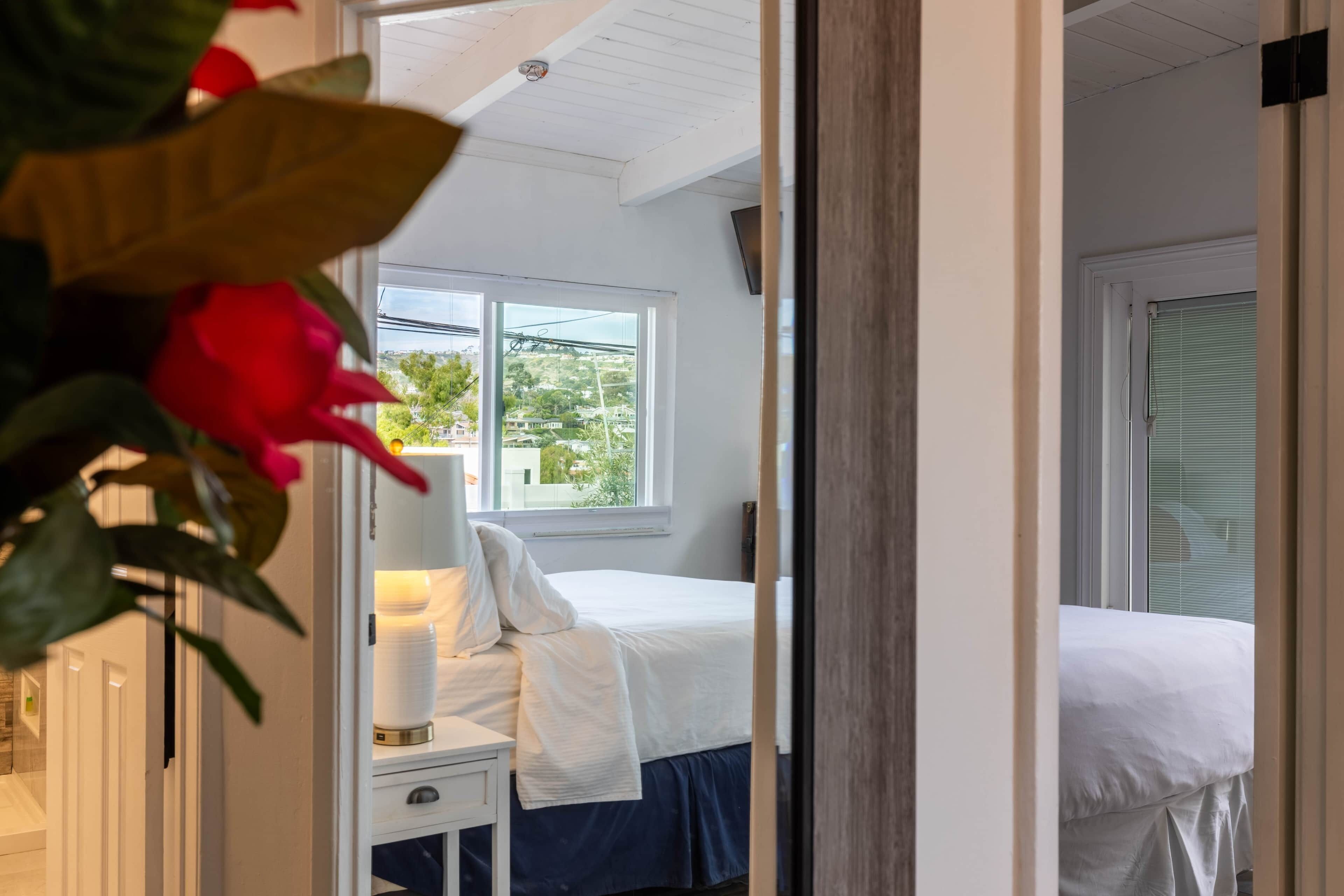 Un dormitorio con cama, mesita de noche, lámpara y ventana con vistas al exterior.