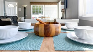 Un coin repas agrémenté d’un centre de table en forme de saladier en bois, de bols blancs et d’une nappe bleue.
