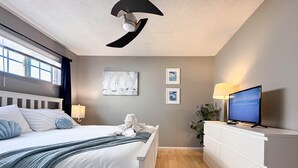 Une chambre d’hôtel moderne équipée d’un lit, d’une télévision, d’un bureau et d’œuvres d’art accrochées au mur.