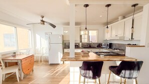 A modern kitchen with white cabinetry, a wooden island, and pendant lighting. - Golden Coast Ocean View Penthouse (San Clemente)