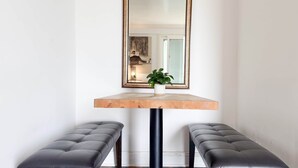 A room with a wooden table, two black leather benches, a mirror with a gold frame, and a potted plant on the table. - Ocean Bluff Hideaway (San Clemente)