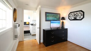 A hallway with a black dresser, a framed painting, and a decorative wall piece. - Ocean Bluff Hideaway (San Clemente)