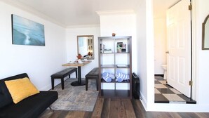 Un salon avec un canapé noir, une table basse, un banc et une bibliothèque.