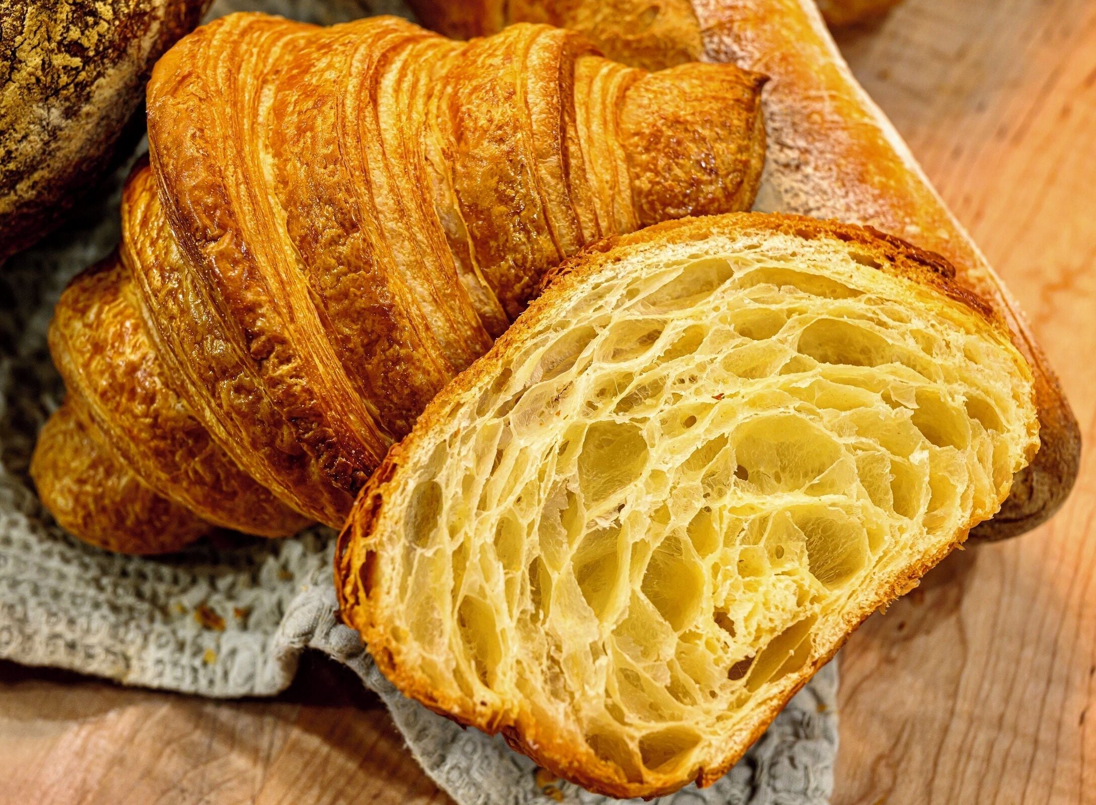 Primer pla d'un croissant amb una textura estratificada i escamosa i una crosta daurada.
