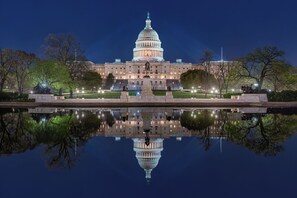 A large, illuminated building with a dome, surrounded by trees and a reflective water body. - Meeting House Boutique Hotel (Falls Church)
