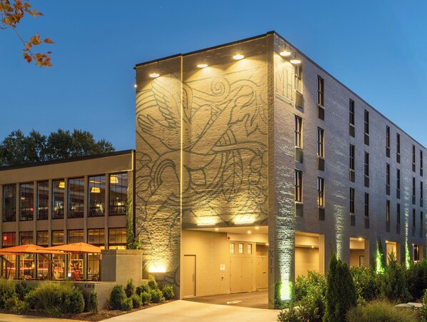 A modern building with a large glass facade, a stone accent wall, and a well-lit entrance. - Meeting House Boutique Hotel (Falls Church)