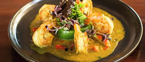 Un plato de comida con camarones y verduras sobre un plato oscuro.