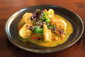 A plate of food with shrimp and vegetables on a dark plate. - Meeting House Boutique Hotel (Falls Church)