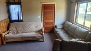 Una habitación compacta con una cama de madera, un banco acolchado, una puerta y una ventana con vistas.