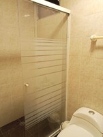 Un baño con cabina de ducha de vidrio, inodoro y paredes de azulejos.