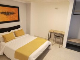 Una habitación de hotel con una cama, un escritorio y una silla.