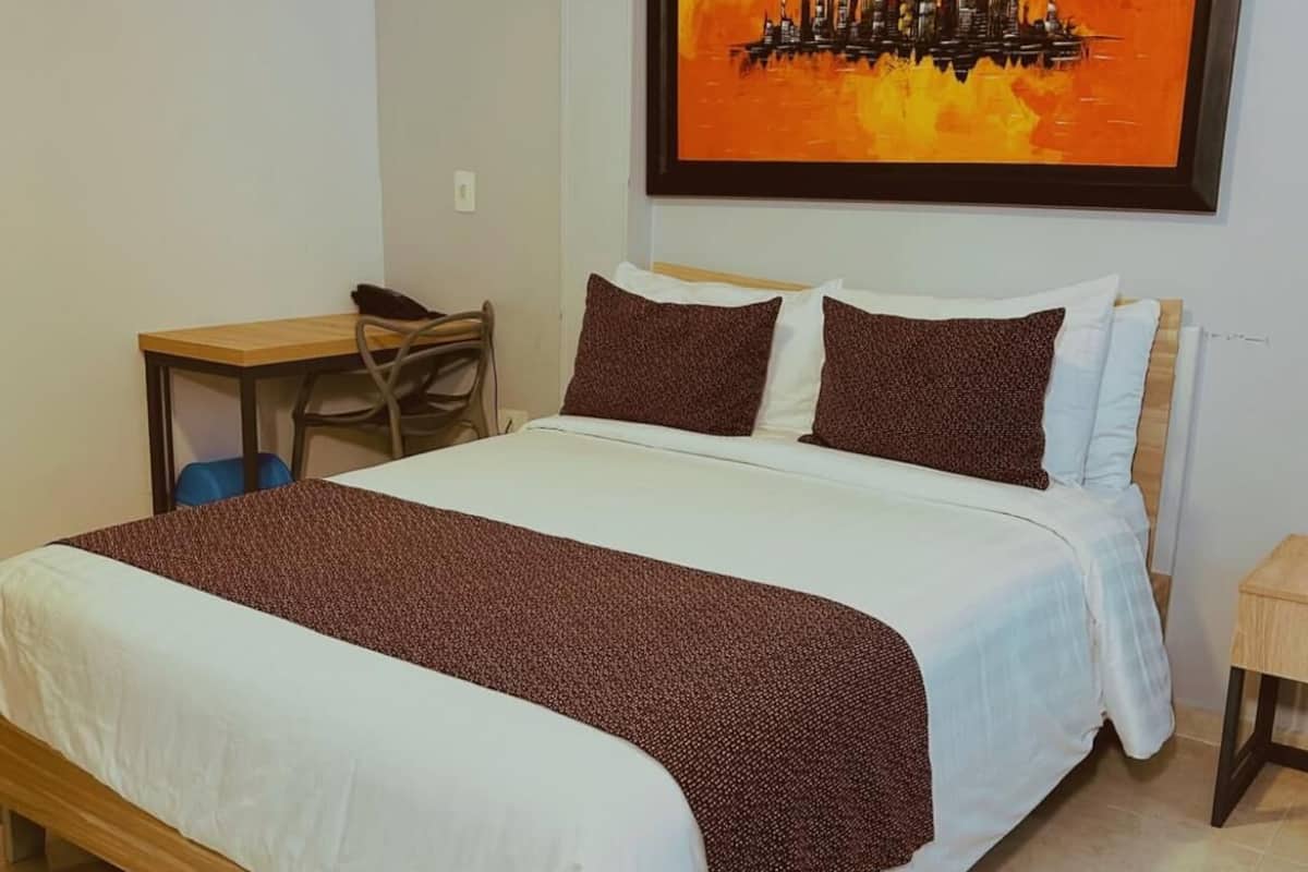 A hotel room with a bed, a desk, and a chair.
