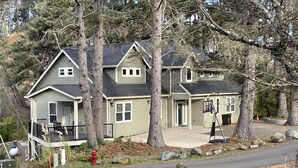 A two-story house with a porch, a basketball hoop, and a driveway.