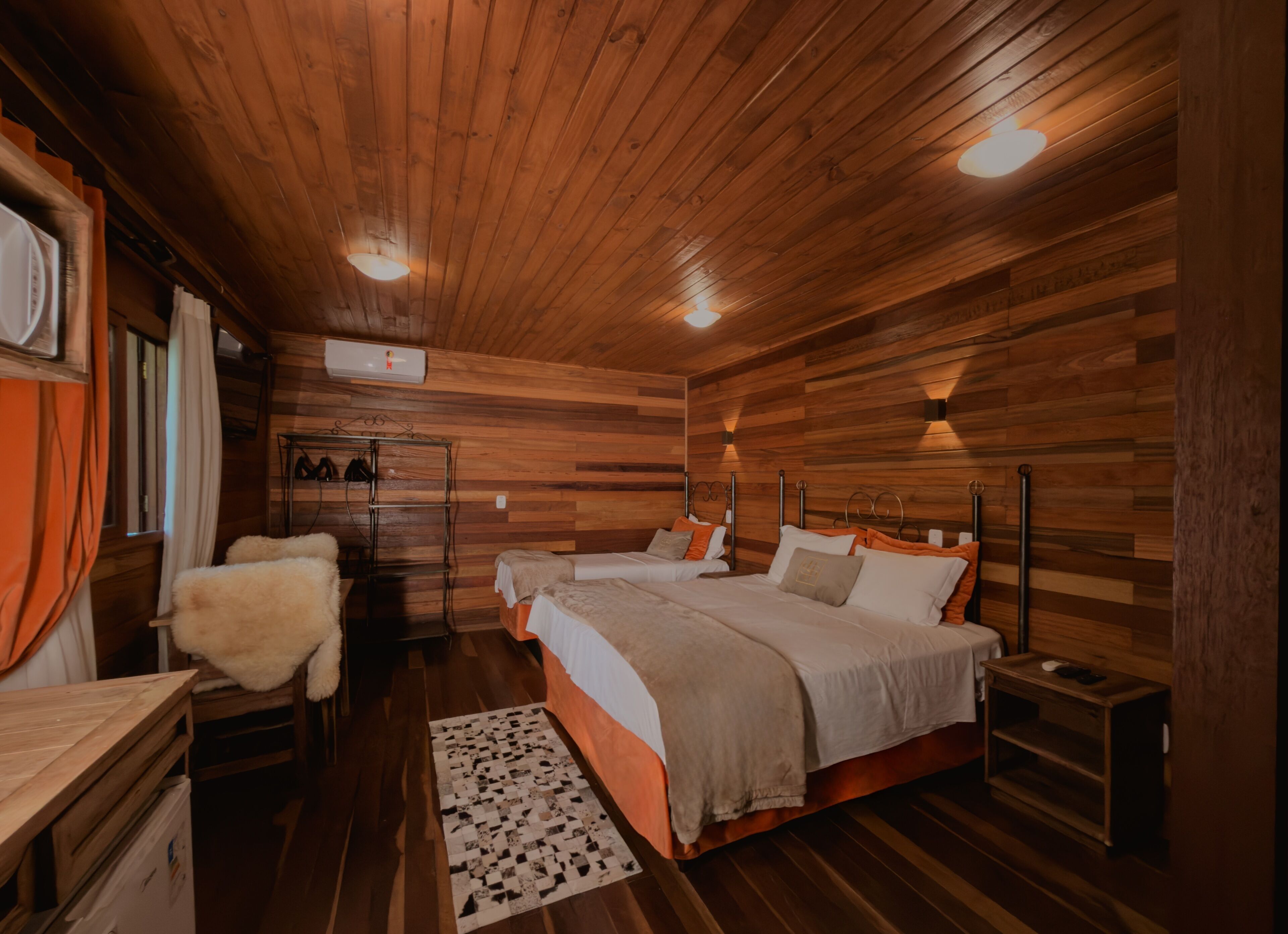 Una habitación con paneles de madera, dos camas, un escritorio y una silla.