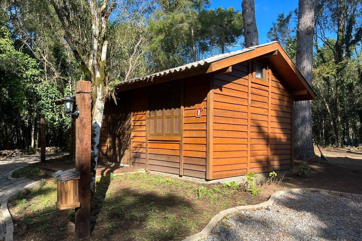 A small wooden cabin with a sloped roof, surrounded by trees.