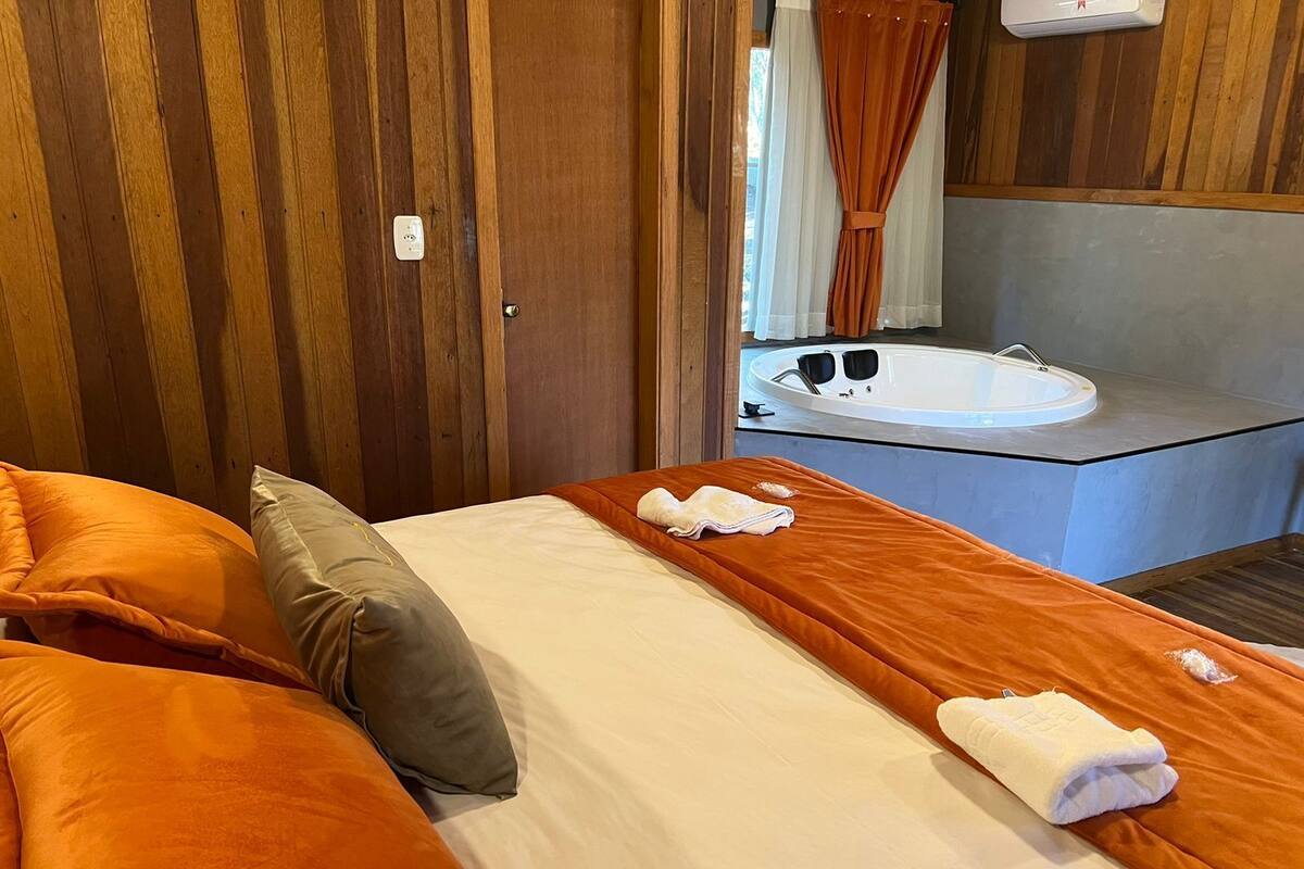 A bedroom with a bed, pillows, a towel, and a bathroom with a bathtub.