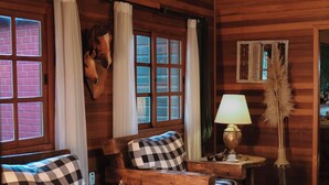 A wooden cabin interior with a checkered sofa, a lamp, and a mounted animal head. - Hotel Cabanas Glamour (Gramado)
