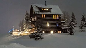 Een blokhut met een met sneeuw bedekte kap, omringd door met sneeuw bedekte bomen.