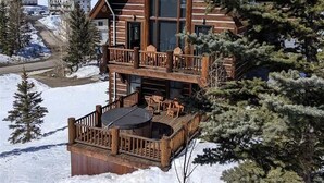 Een vakantiehuisje van hout met een balkon, omgeven door sneeuw en bomen.