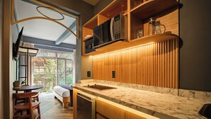 Una cocina moderna con armarios de madera, encimera de mármol y microondas integrado.