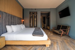 Une chambre à coucher moderne avec un grand lit, une tête de lit en bois et un téléviseur fixé au mur.