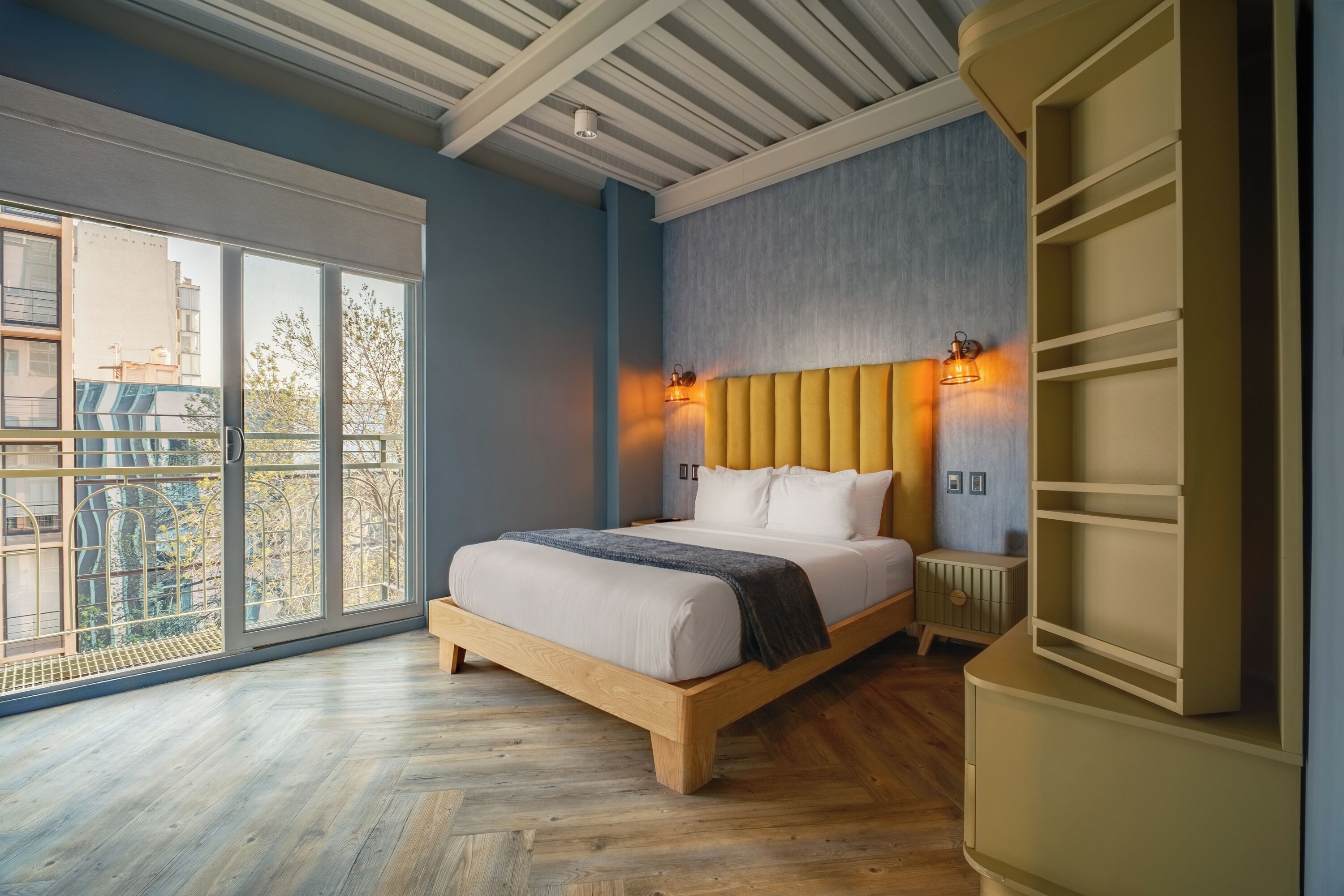 Un dormitorio con un gran ventanal, una cama de madera y un armario empotrado.