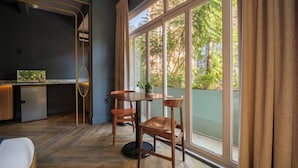 Una habitación moderna con un ventanal grande, una pequeña cocina y una mesa de comedor con sillas.