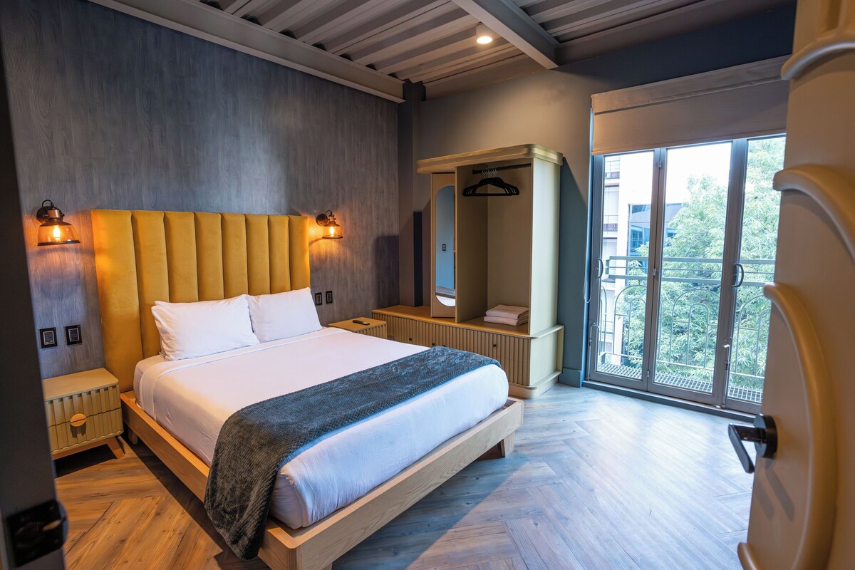 Une chambre moderne avec un grand lit, des lampes de chevet, une armoire et un balcon avec vue.
