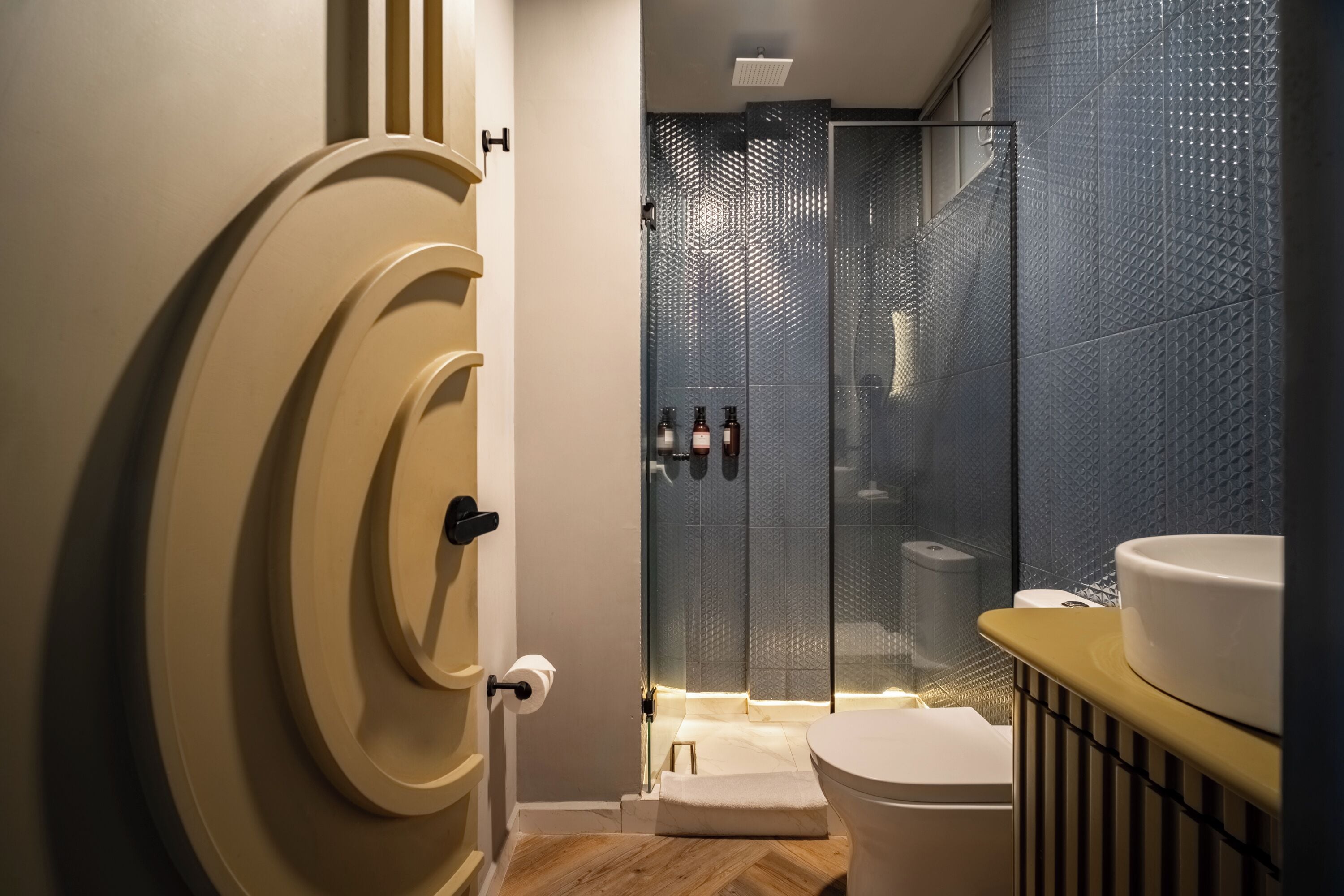A modern bathroom with a glass shower enclosure, a toilet, and a sink.