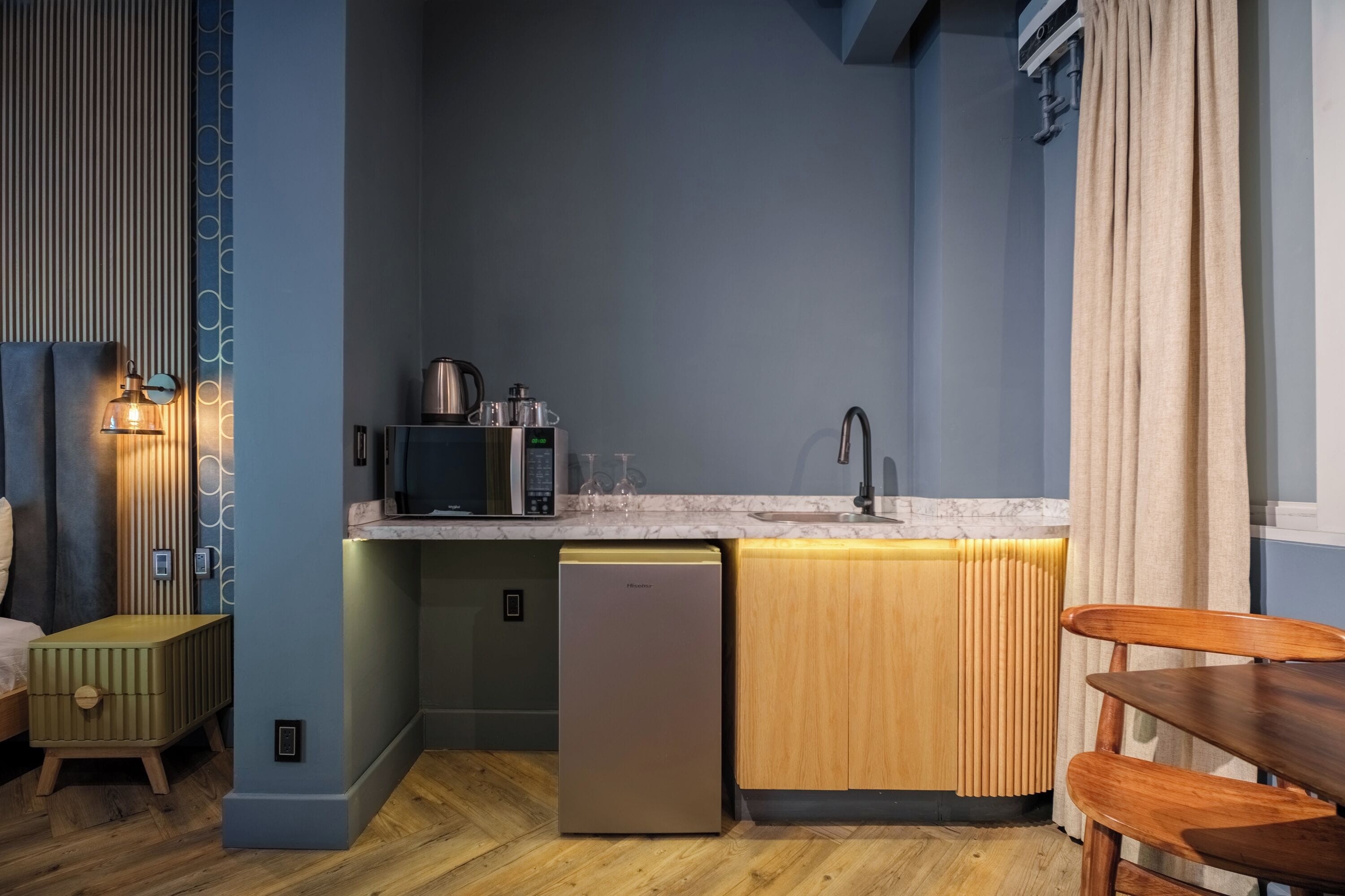 Una cocina compacta con microondas integrado, un lavamanos y un refrigerador.