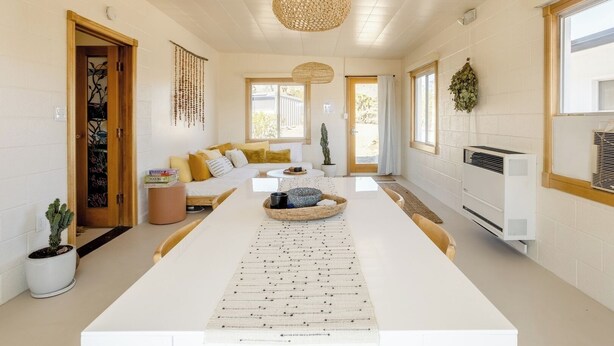 A modern living room with a white sofa, a coffee table, and a hanging light fixture.